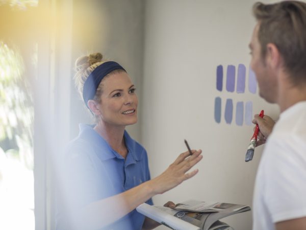 Couple holding brochure discussing paint colours on wall