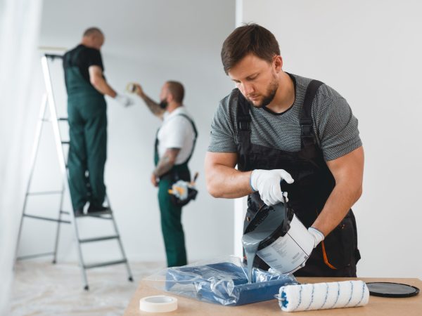 Efficient renovation crew painting white walls of new build home