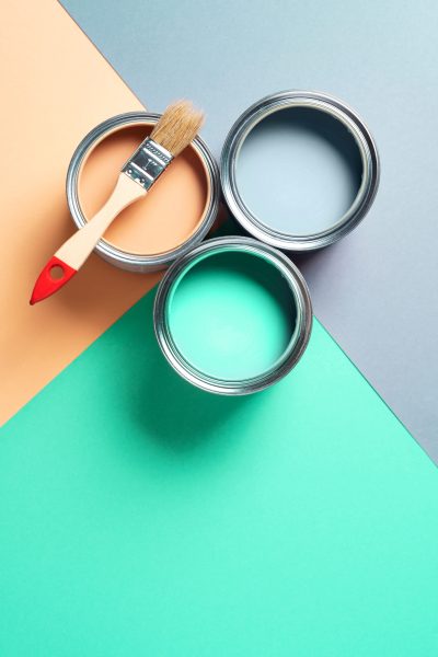 Metal paint cans and paint brushes on multicolor background. Top view. Copy space. Trendy green color concept.