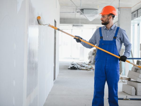 painter man painting the wall, with paint roller.