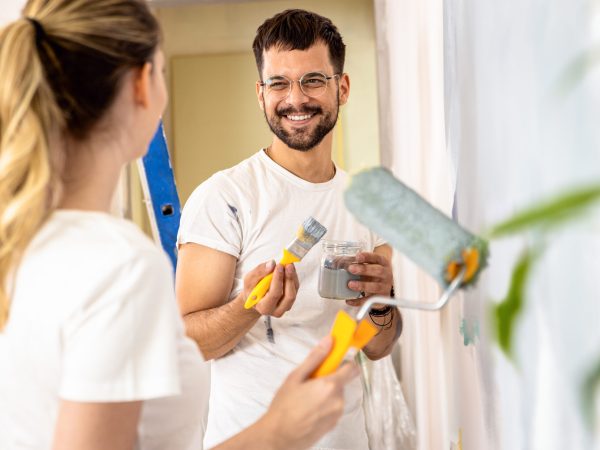Young couple painting wall in their home.